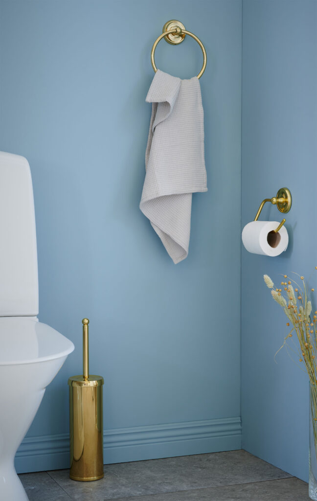 handduksring, wc-borste, toalettpappershållare i polerad mässing i blått badrum